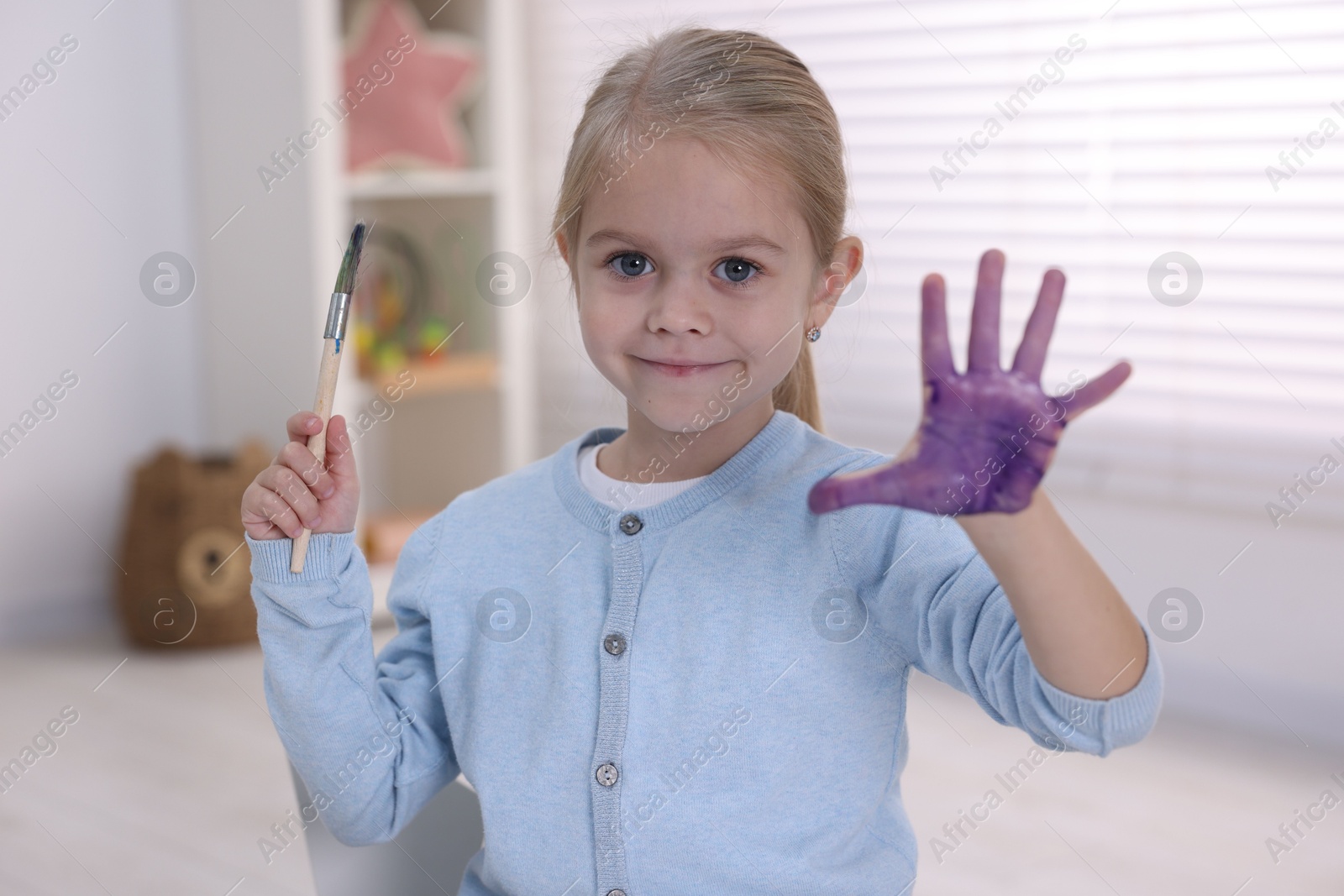 Photo of Cute girl drawing with palm in kindergarten