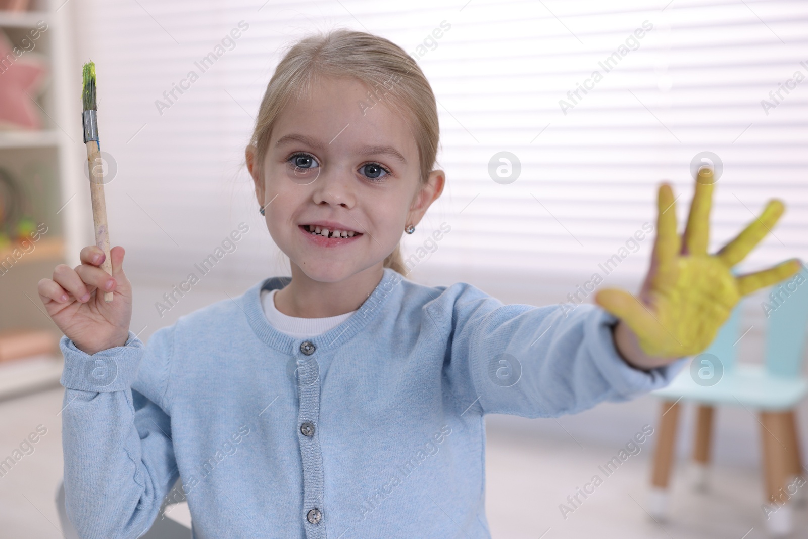 Photo of Happy girl drawing with palm in kindergarten