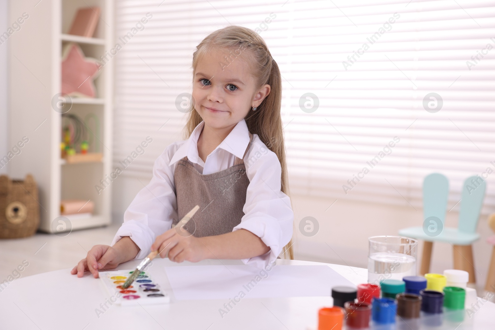 Photo of Cute girl drawing at white table in kindergarten