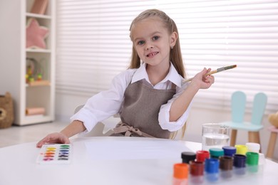 Smiling girl drawing at white table in kindergarten