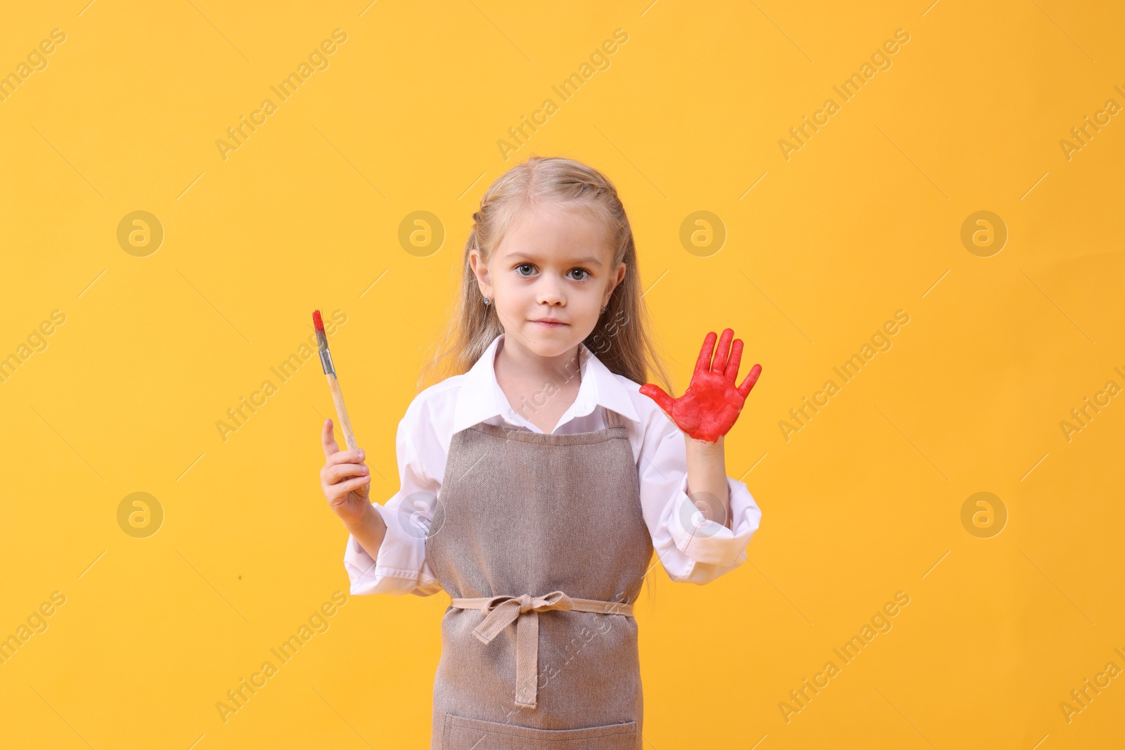 Photo of Cute girl drawing with palm on orange background