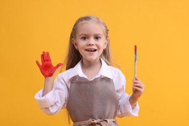 Photo of Happy girl drawing with palm on orange background