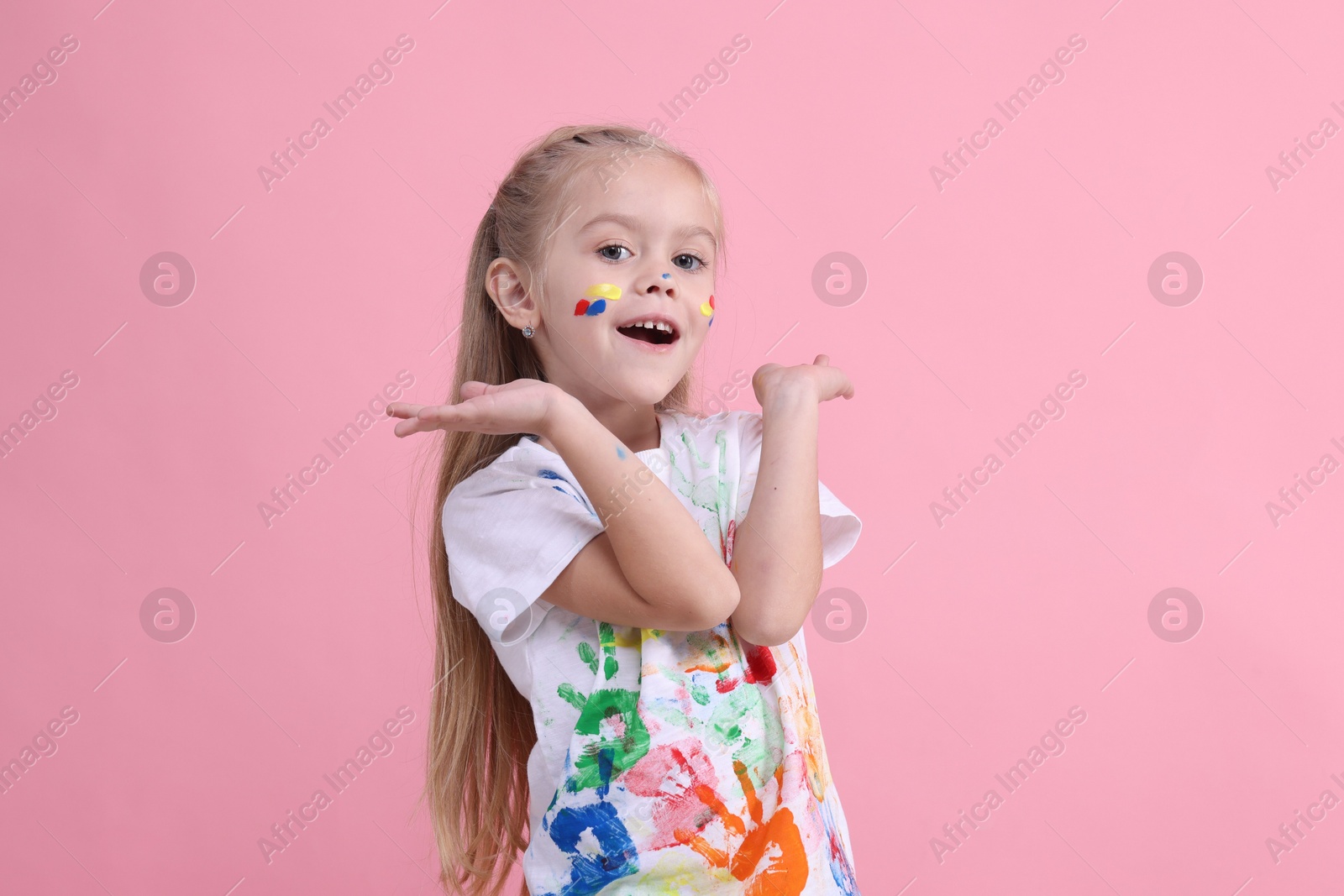 Photo of Portrait of happy girl smeared in paint on pink background