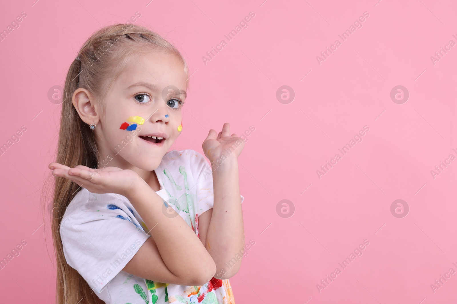 Photo of Portrait of happy girl smeared in paint on pink background. Space for text