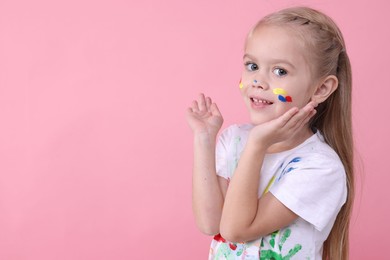 Photo of Portrait of happy girl smeared in paint on pink background. Space for text