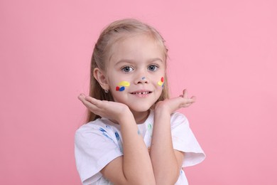 Photo of Portrait of happy girl smeared in paint on pink background