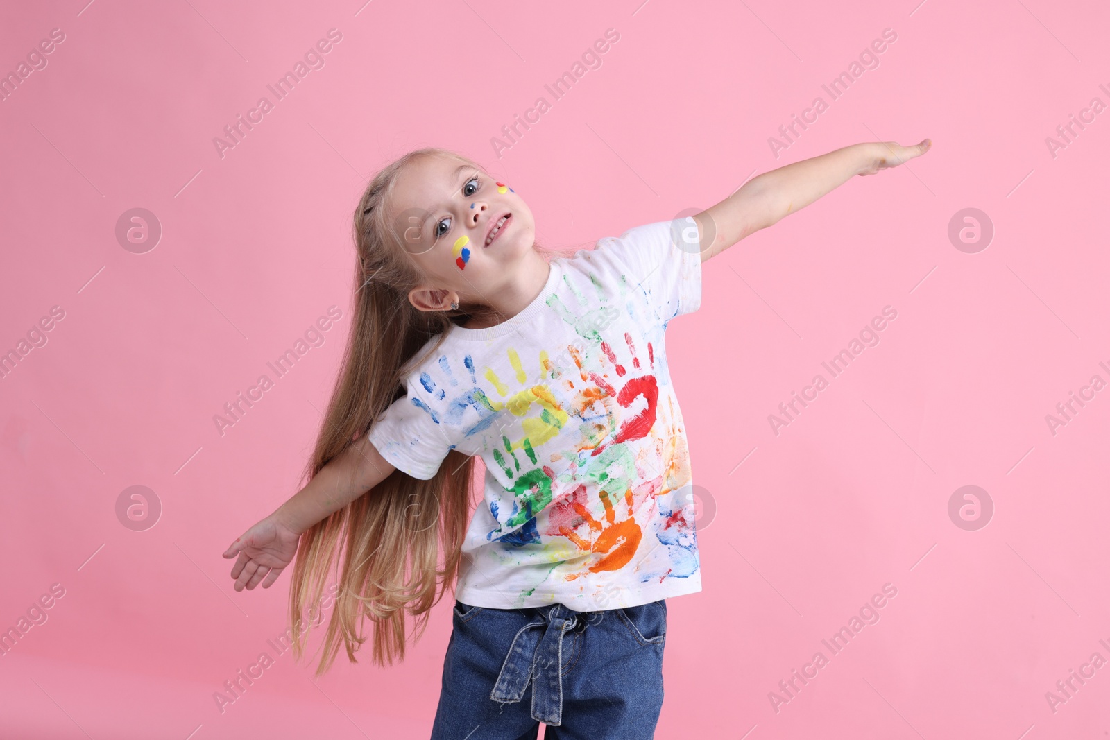 Photo of Portrait of happy girl smeared in paint on pink background