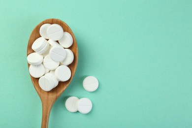 Photo of Antibiotic pills in spoon on turquoise background, top view. Space for text