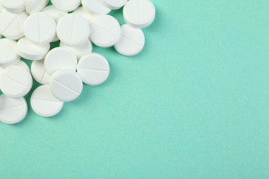 Photo of Pile of antibiotic pills on turquoise background, top view. Space for text