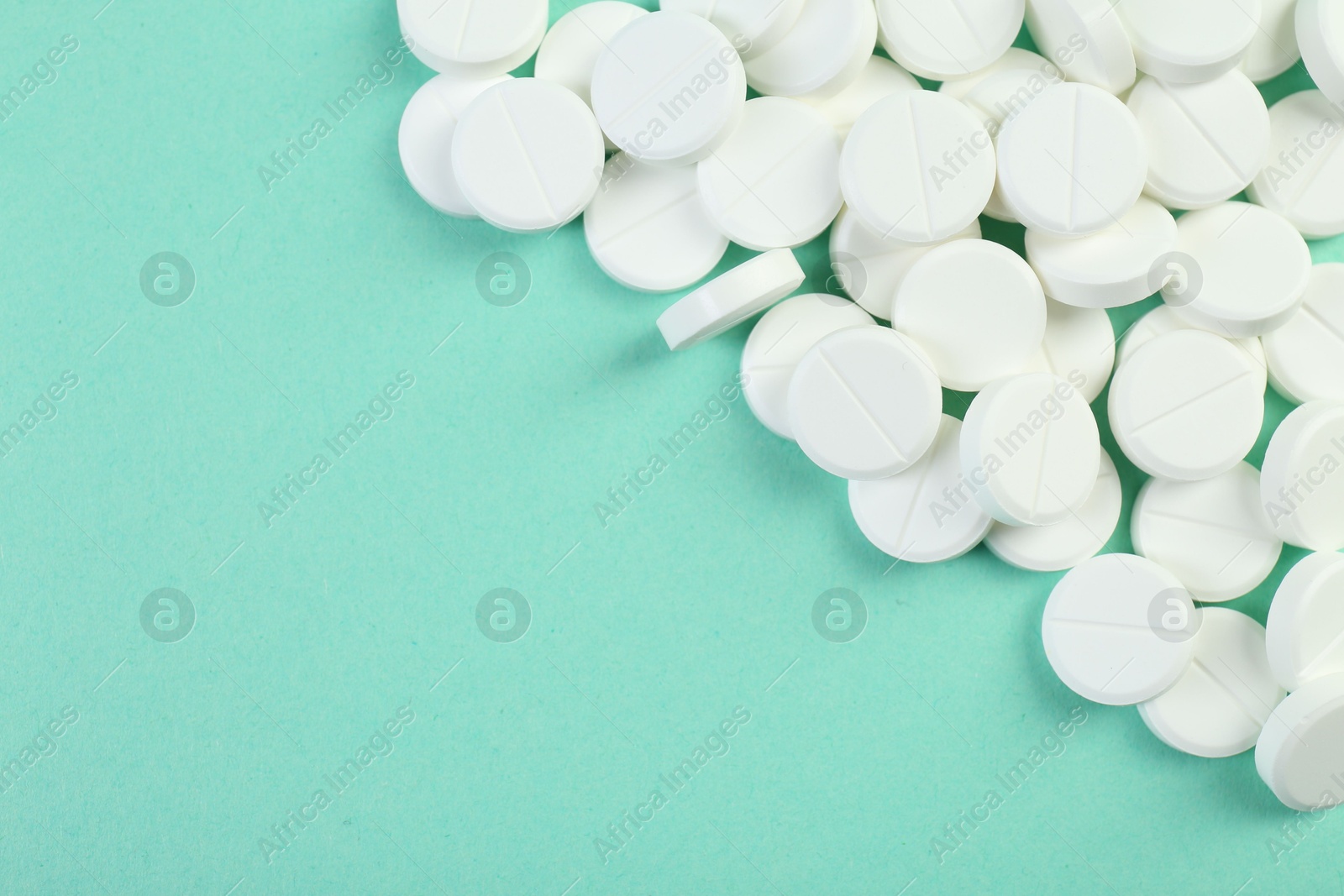 Photo of Pile of antibiotic pills on turquoise background, top view. Space for text