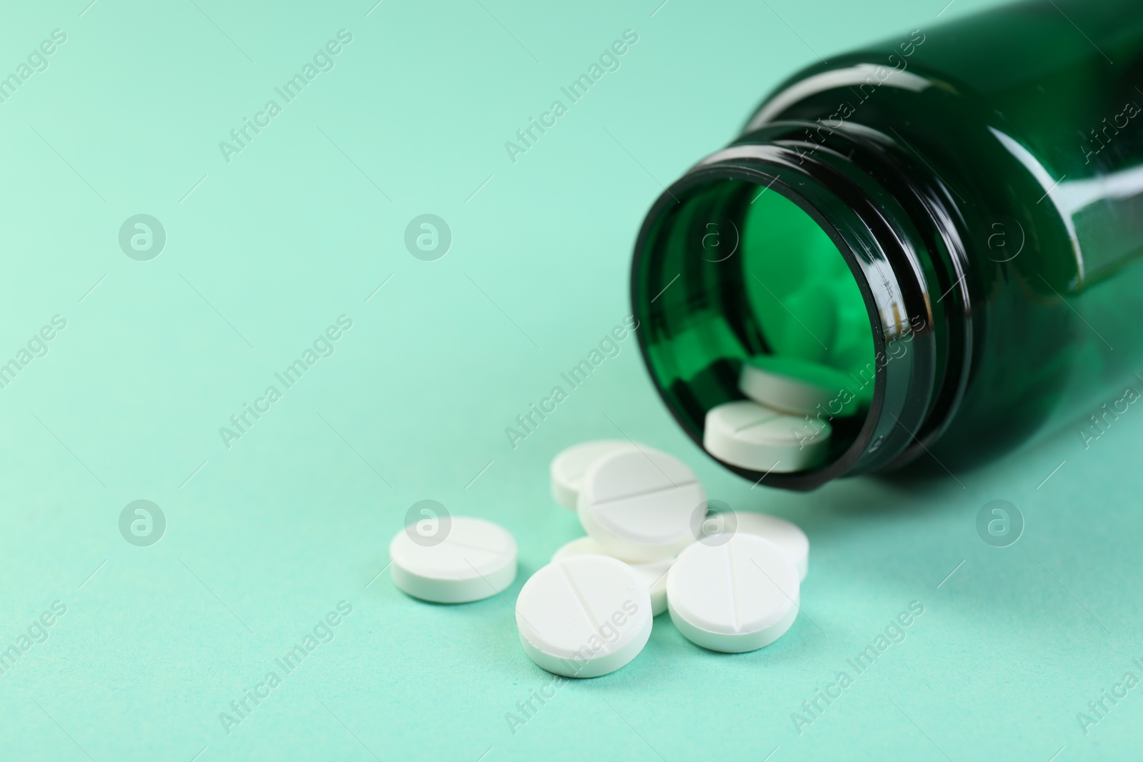 Photo of Medical bottle with antibiotic pills on turquoise background, closeup. Space for text