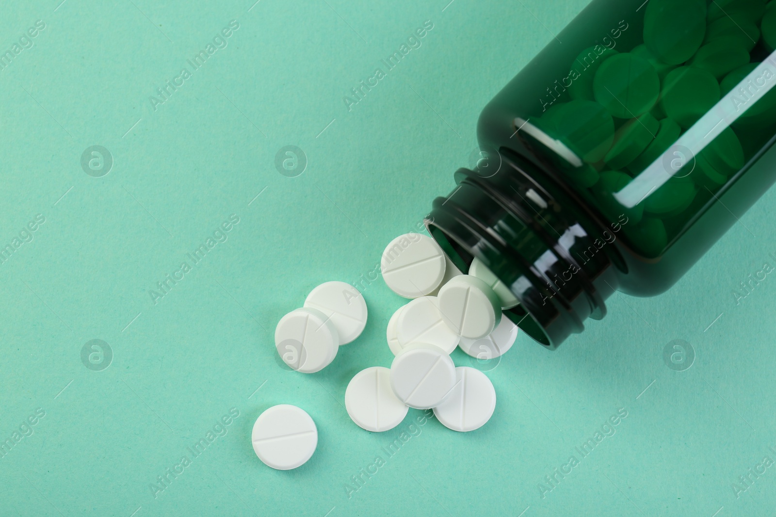 Photo of Medical bottle with antibiotic pills on turquoise background, top view. Space for text