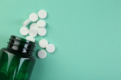 Photo of Medical bottle with antibiotic pills on turquoise background, top view. Space for text