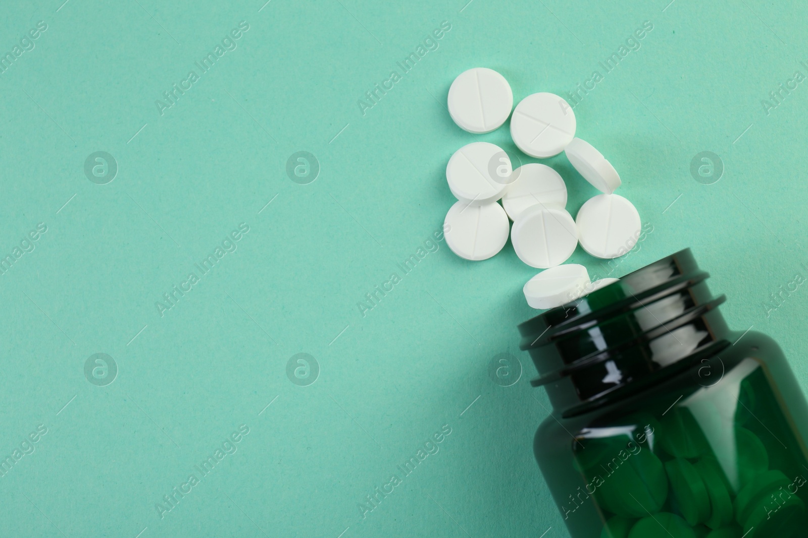 Photo of Medical bottle with antibiotic pills on turquoise background, top view. Space for text