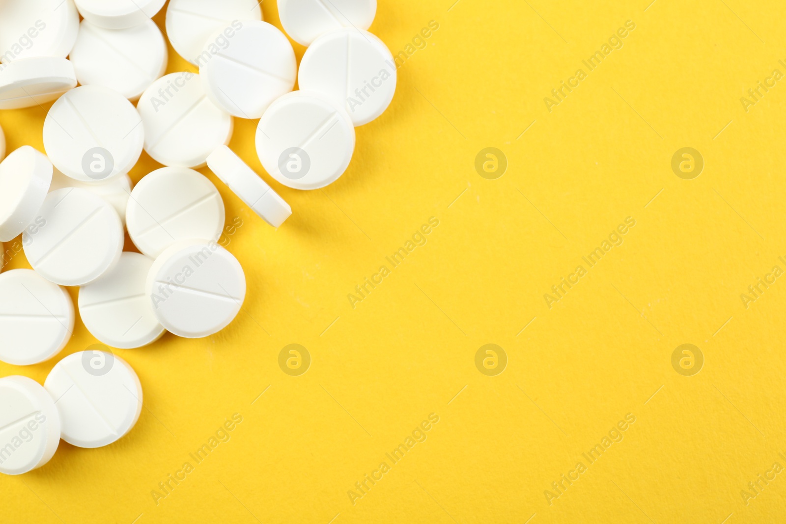 Photo of Pile of antibiotic pills on yellow background, top view. Space for text