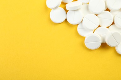 Photo of Pile of antibiotic pills on yellow background, top view. Space for text