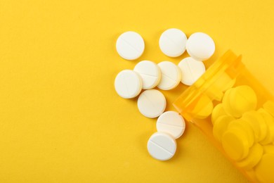 Photo of Medical bottle with antibiotic pills on yellow background, top view. Space for text