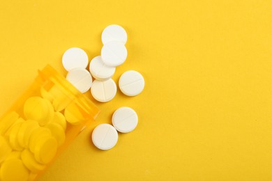 Photo of Medical bottle with antibiotic pills on yellow background, top view. Space for text