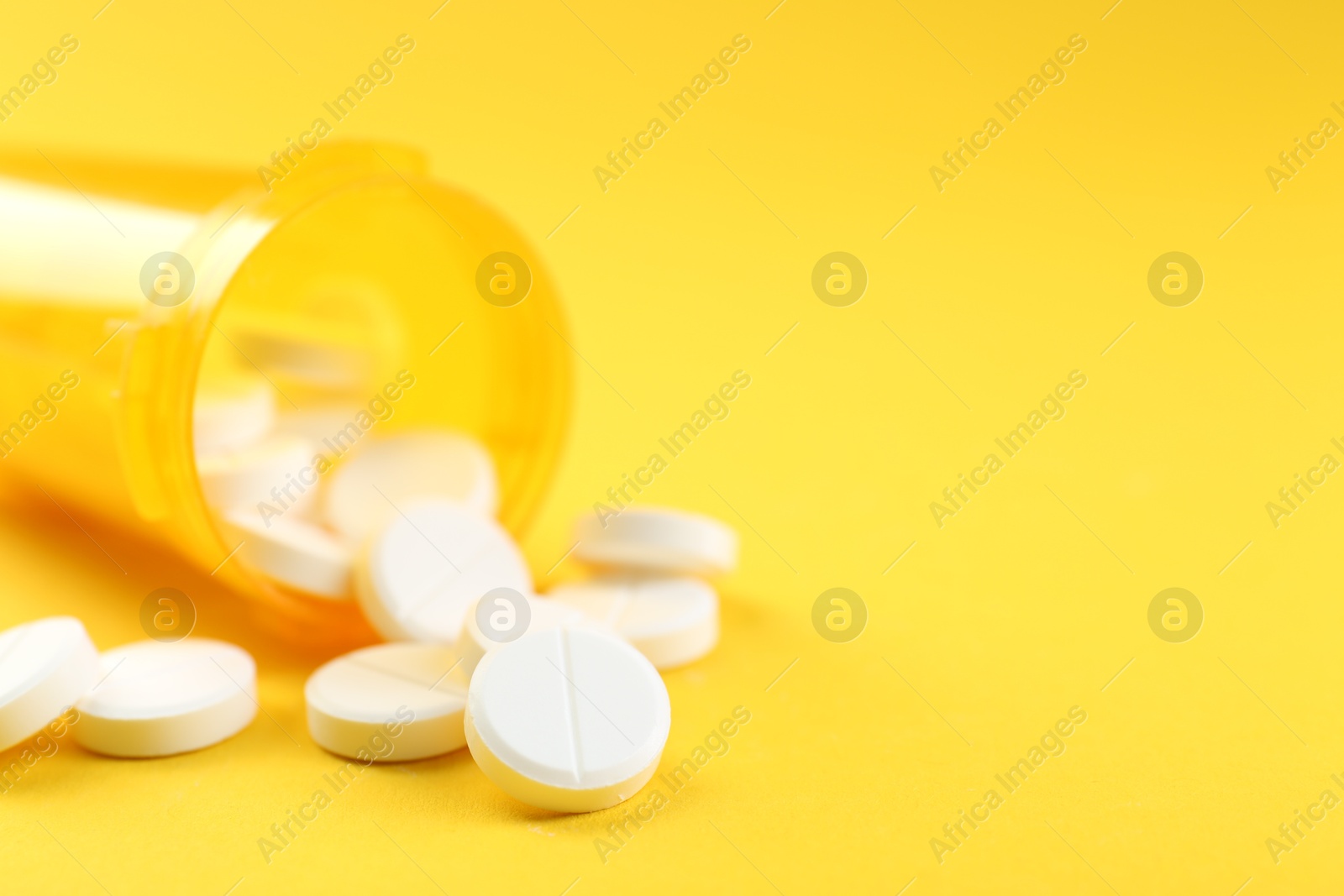 Photo of Medical bottle with antibiotic pills on yellow background, selective focus. Space for text