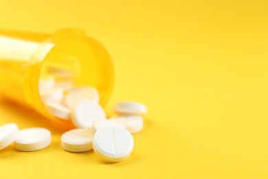 Photo of Medical bottle with antibiotic pills on yellow background, selective focus. Space for text