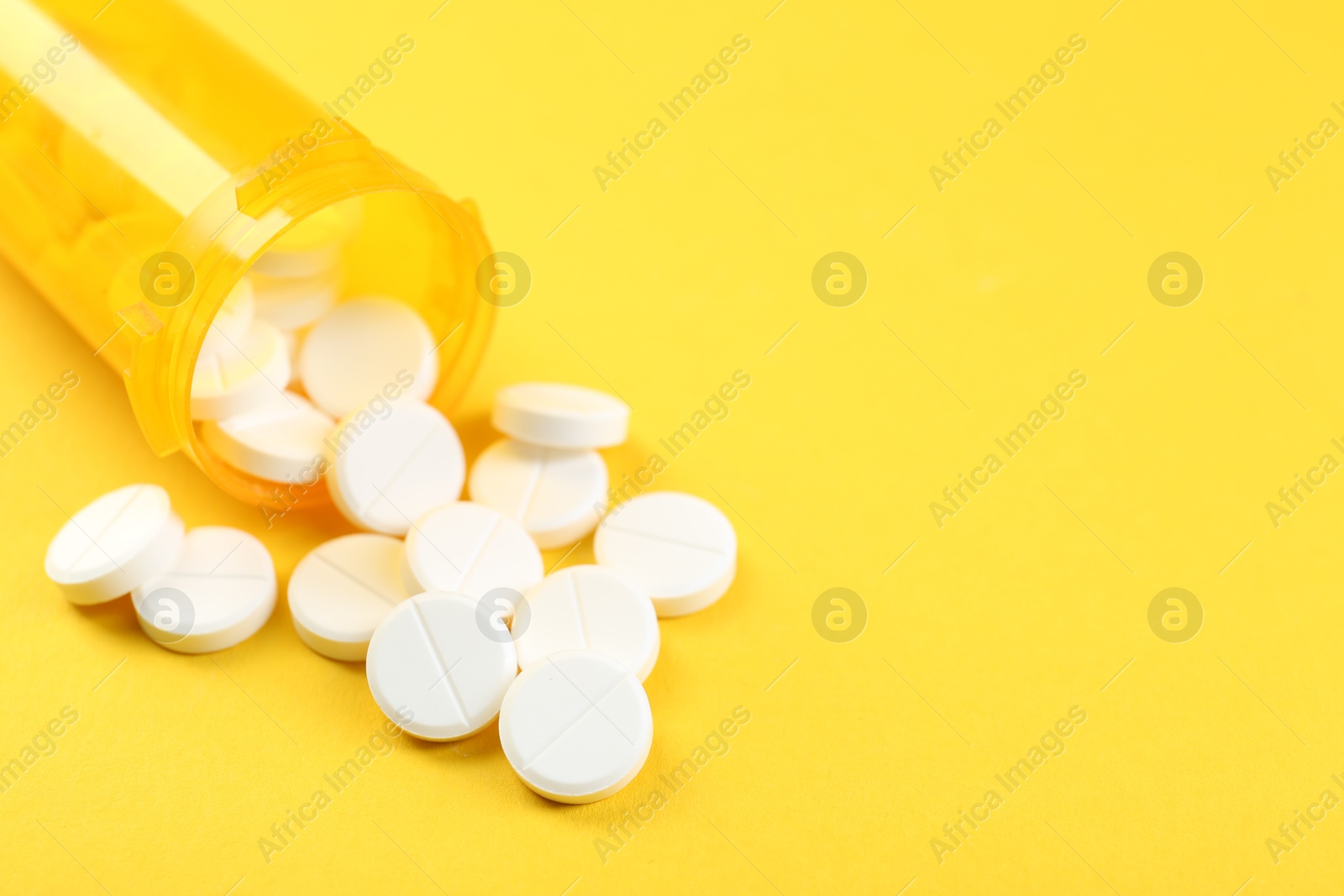 Photo of Medical bottle with antibiotic pills on yellow background, closeup. Space for text