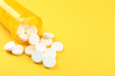 Photo of Medical bottle with antibiotic pills on yellow background, closeup. Space for text