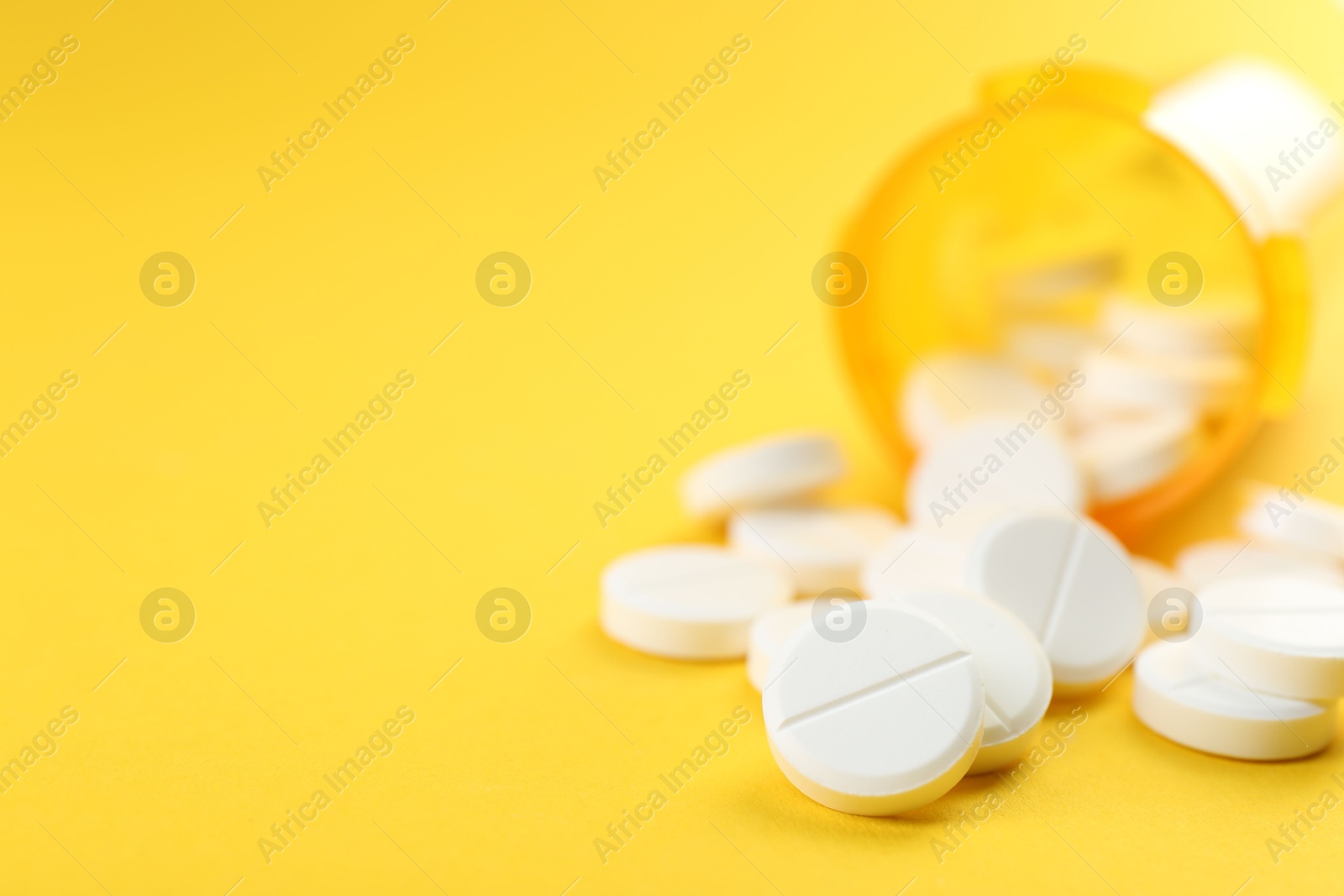 Photo of Medical bottle with antibiotic pills on yellow background, selective focus. Space for text