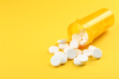 Photo of Medical bottle with antibiotic pills on yellow background, closeup. Space for text