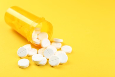 Photo of Medical bottle with antibiotic pills on yellow background, closeup. Space for text