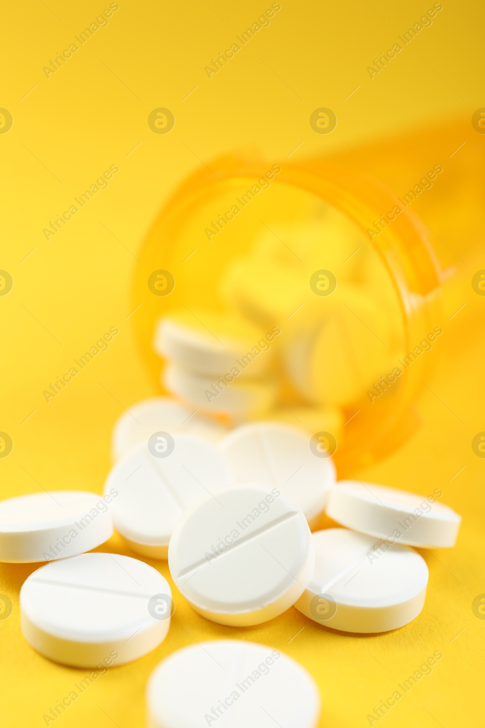 Photo of Medical bottle with antibiotic pills on yellow background, selective focus