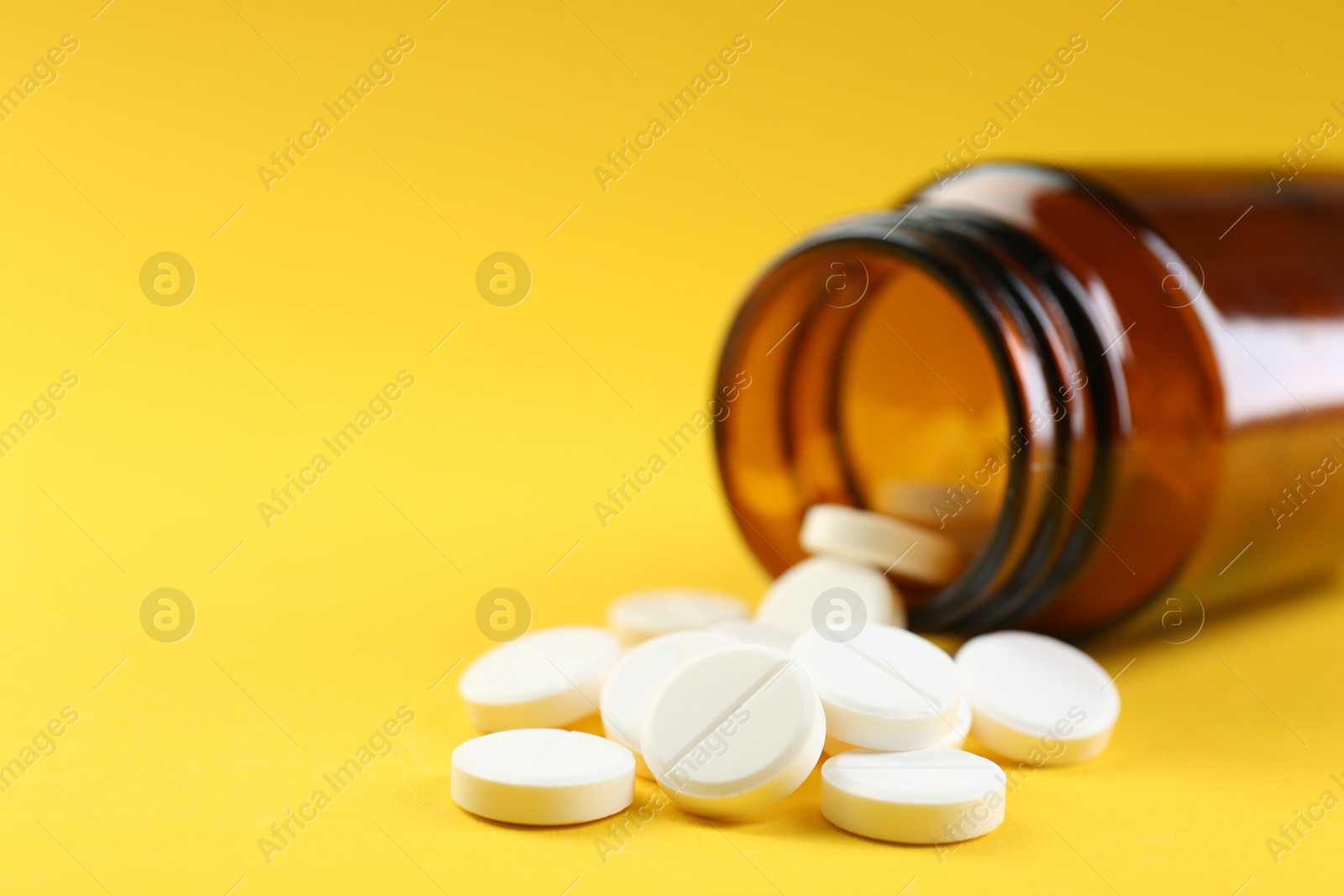 Photo of Medical bottle with antibiotic pills on yellow background, closeup. Space for text