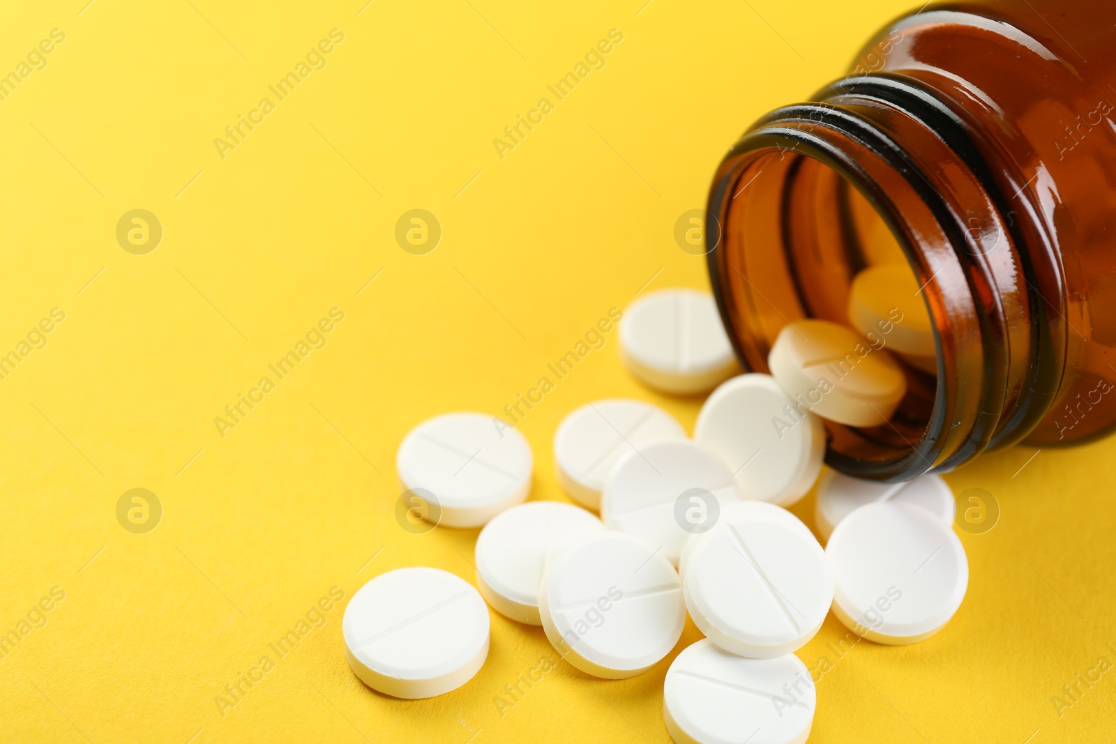 Photo of Medical bottle with antibiotic pills on yellow background, closeup. Space for text