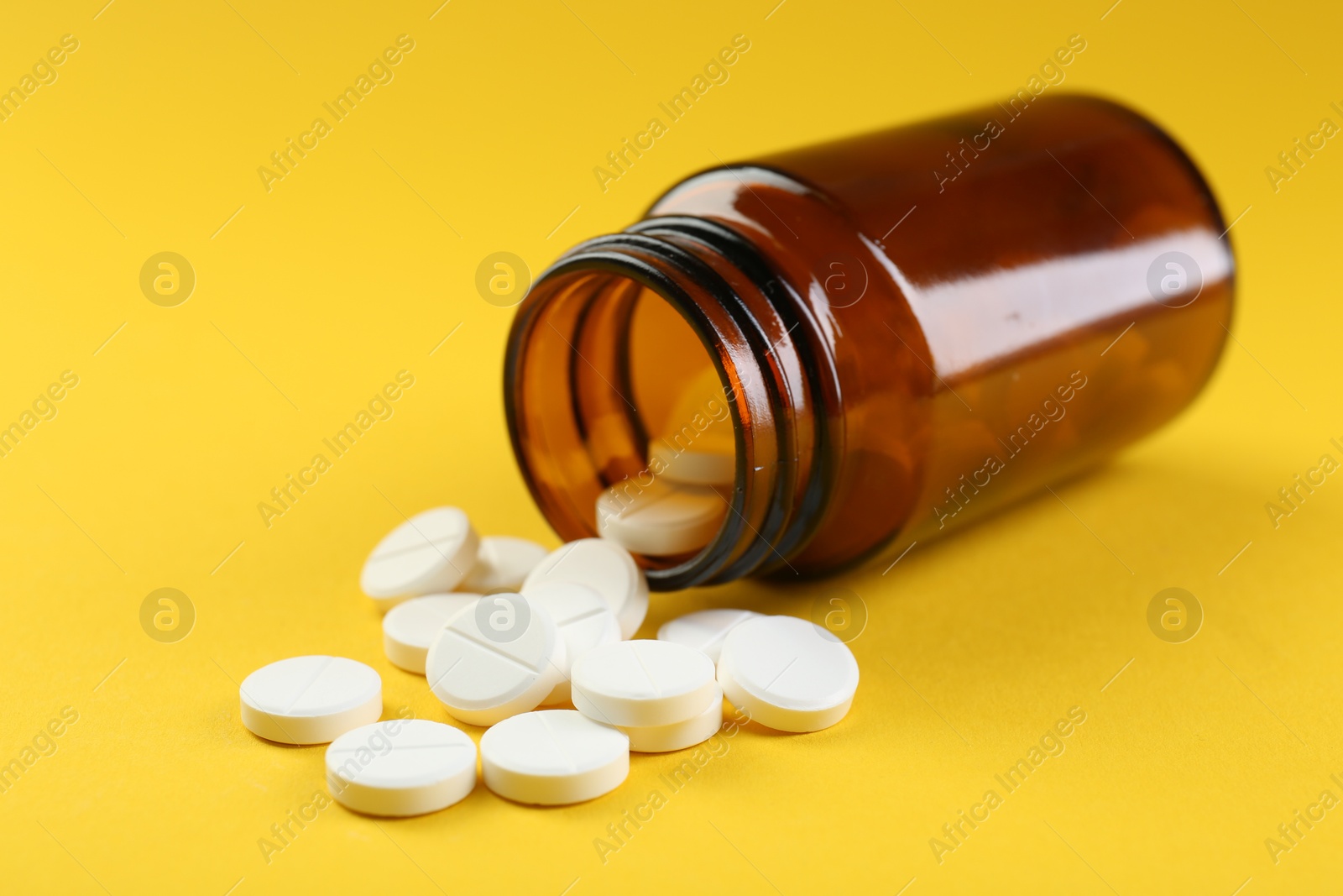 Photo of Medical bottle with antibiotic pills on yellow background, closeup