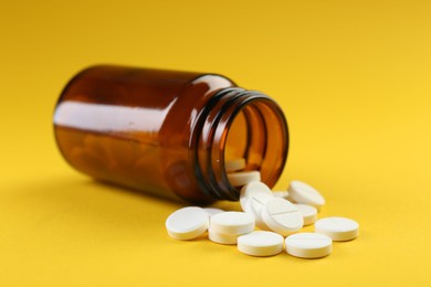 Photo of Medical bottle with antibiotic pills on yellow background, closeup