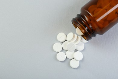 Photo of Medical bottle with antibiotic pills on grey background, top view. Space for text