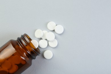 Photo of Medical bottle with antibiotic pills on grey background, top view. Space for text