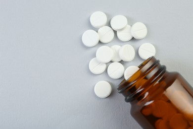 Photo of Medical bottle with antibiotic pills on grey background, top view. Space for text