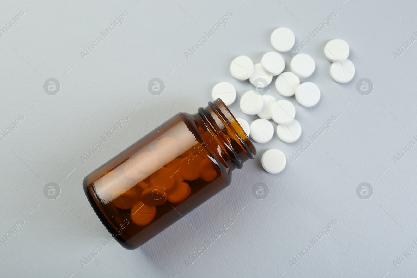 Photo of Medical bottle with antibiotic pills on grey background, top view