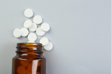 Photo of Medical bottle with antibiotic pills on grey background, top view. Space for text