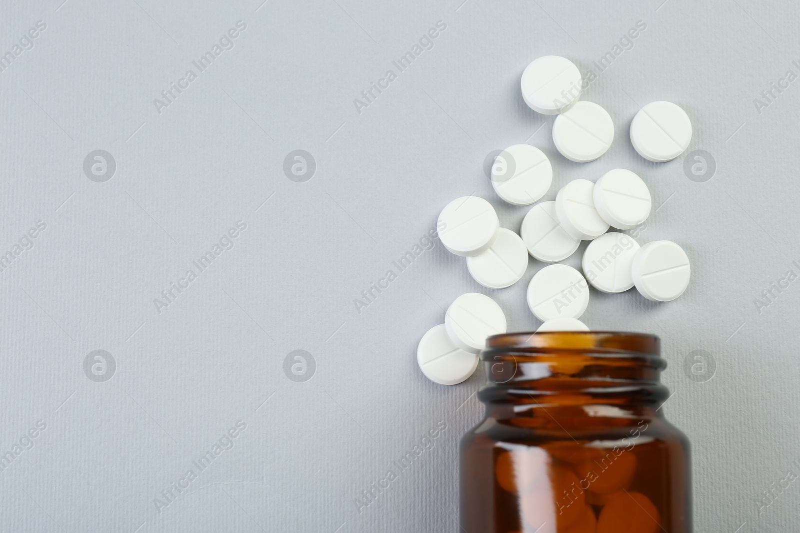 Photo of Medical bottle with antibiotic pills on grey background, top view. Space for text