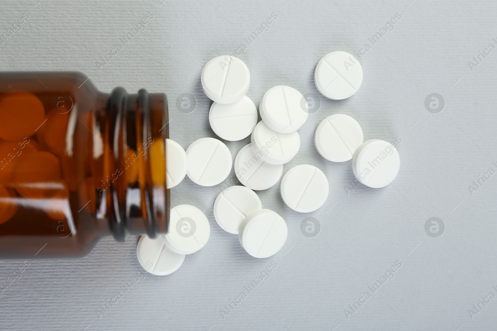 Photo of Medical bottle with antibiotic pills on grey background, top view