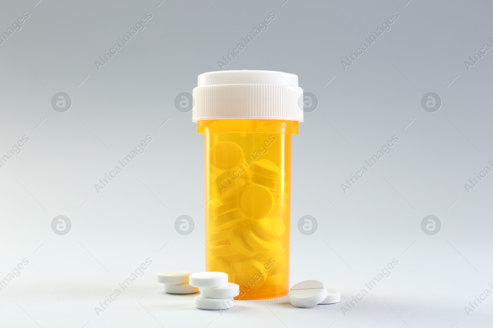 Photo of Medical bottle with antibiotic pills on grey background