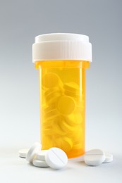 Photo of Medical bottle with antibiotic pills on grey background