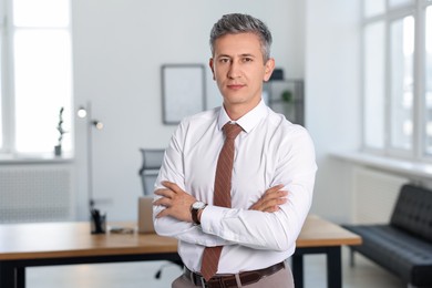 Portrait of middle aged man with crossed arms in office