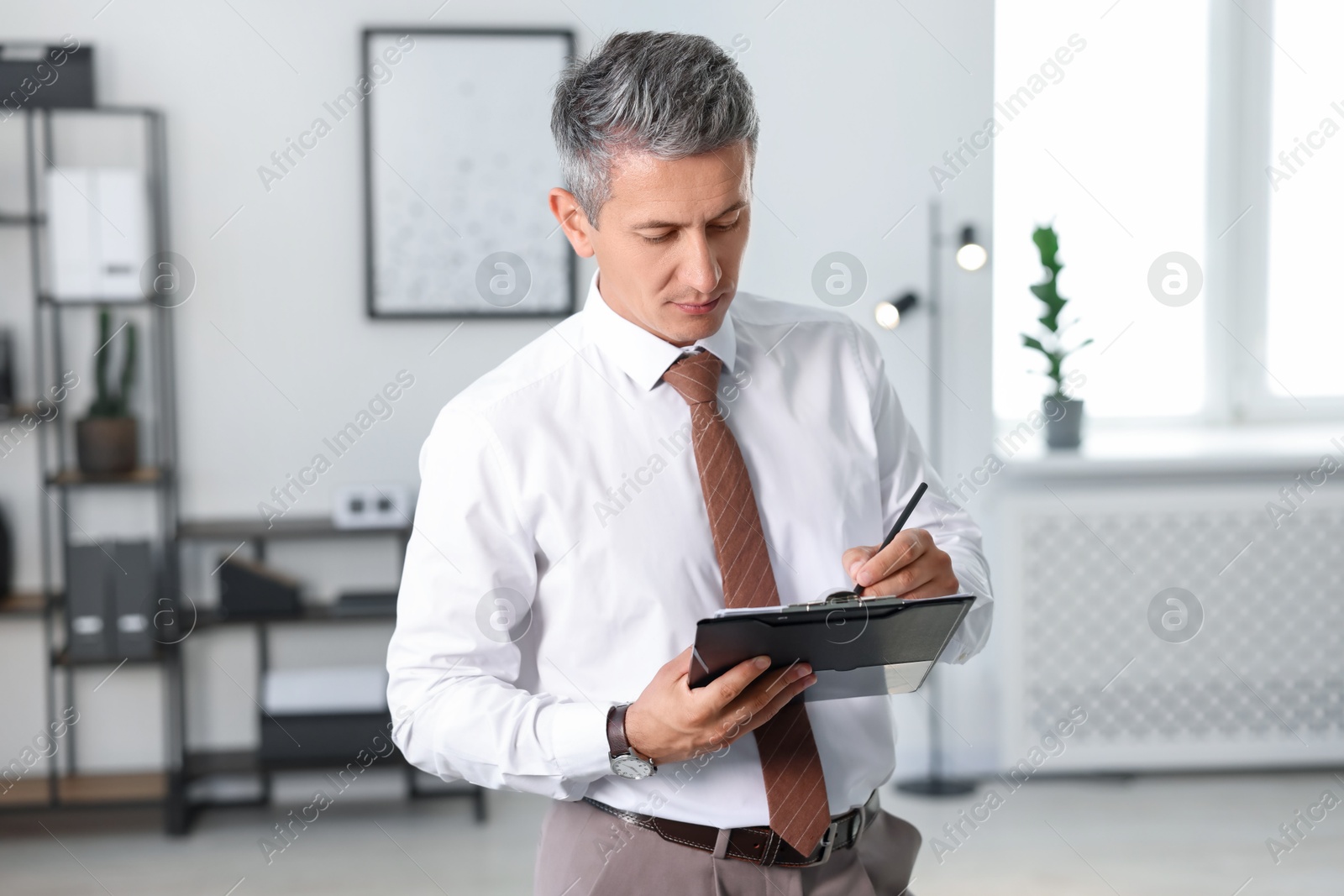 Photo of Middle aged man working with clipboard in office