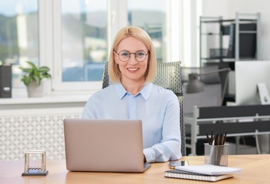 Photo of Portrait of smiling middle aged woman at table in office