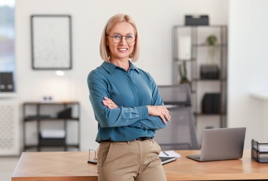 Portrait of smiling middle aged woman with crossed arms in office