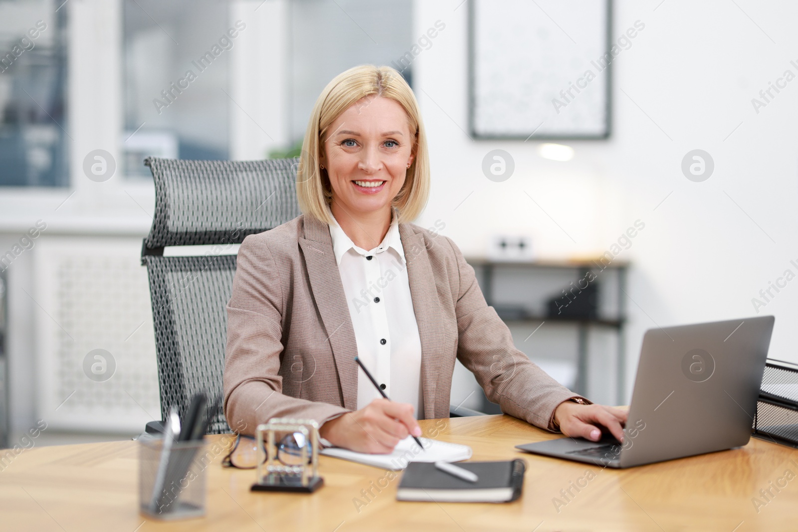 Photo of Portrait of smiling middle aged woman at table in office