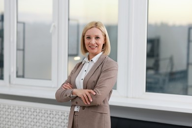 Portrait of smiling middle aged woman with crossed arms in office