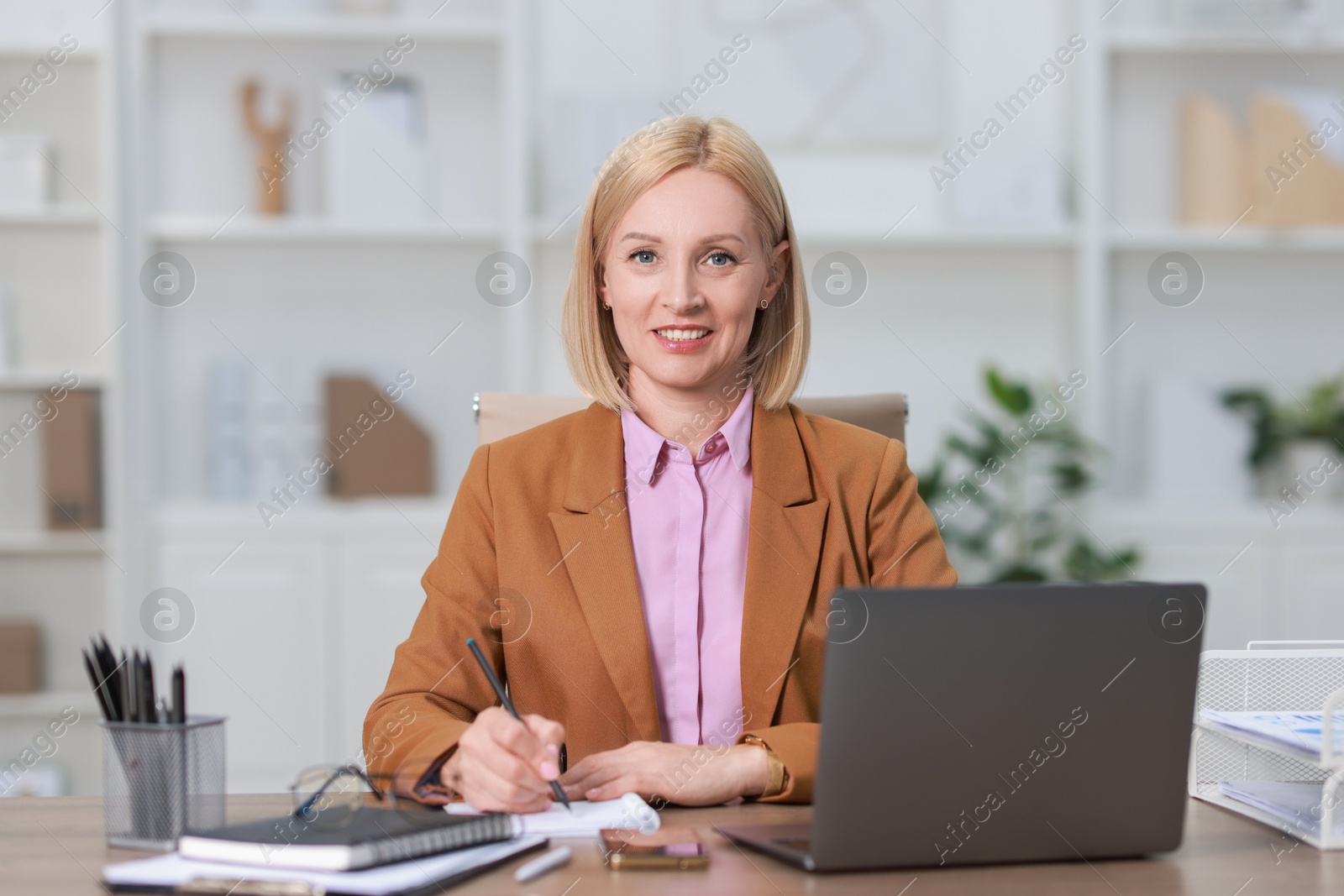 Photo of Portrait of smiling middle aged woman at table in office